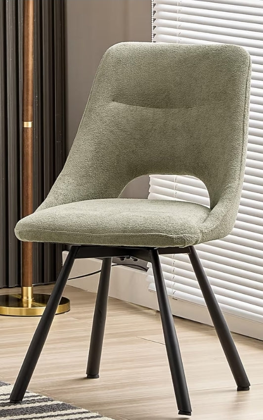 Green chair with black legs in a room with a window and lamp.