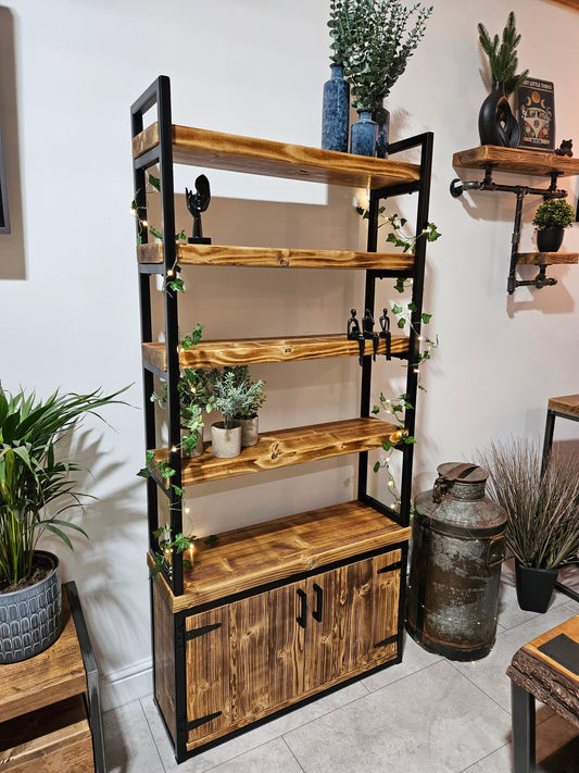 Wooden bookshelf with metal accents in a room with plants and décor.