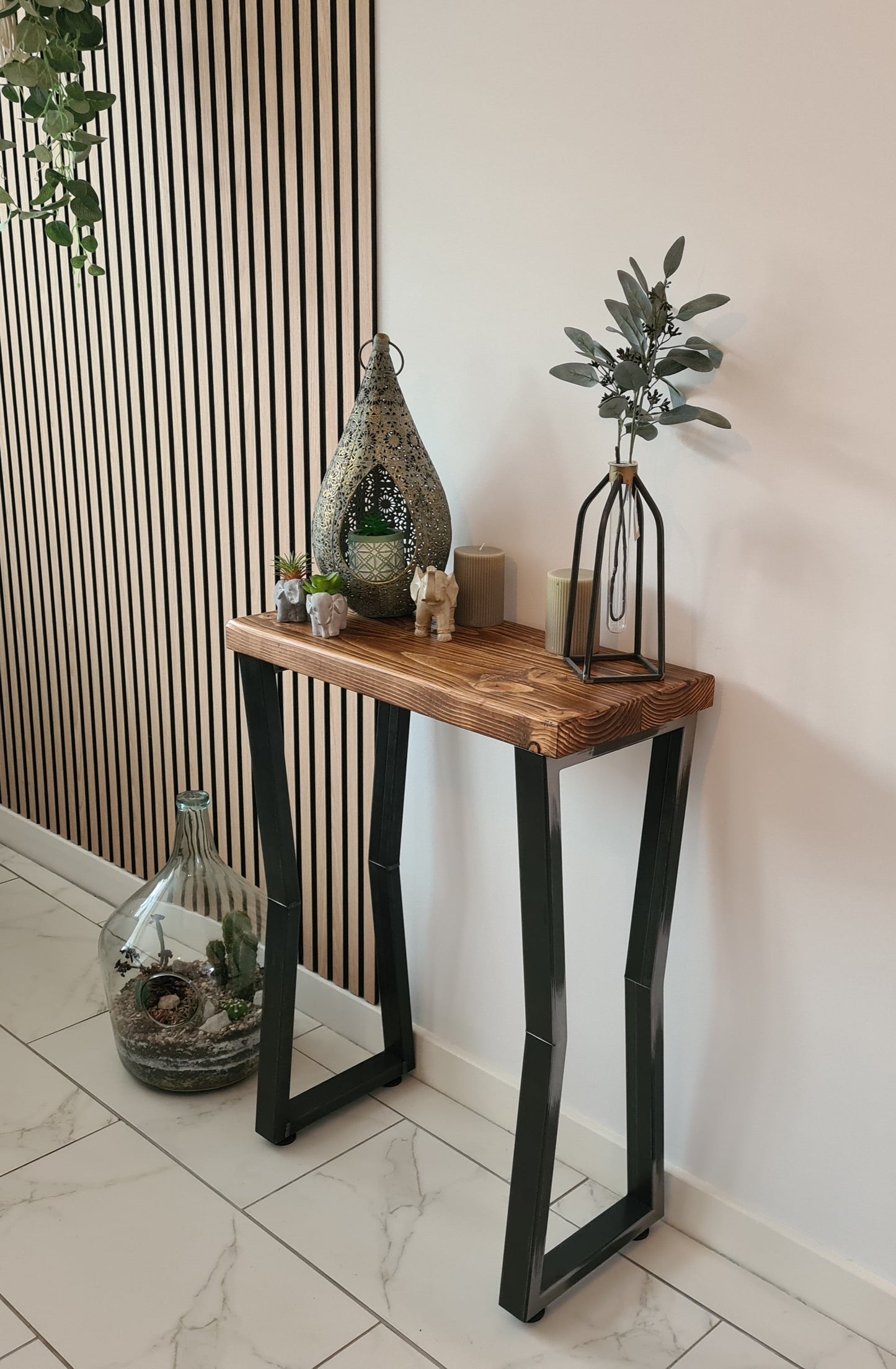 Wooden console table with decorative items against a wall with vertical slats.